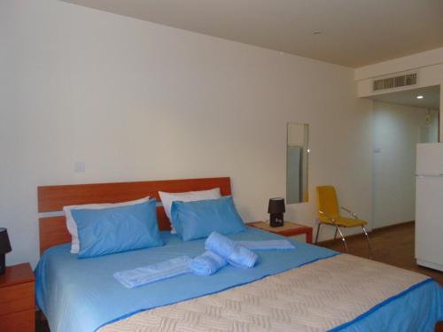 une chambre avec un grand lit avec des oreillers bleus dans l'établissement Ithaki Phinikoudes Apartment No. 107, à Larnaka