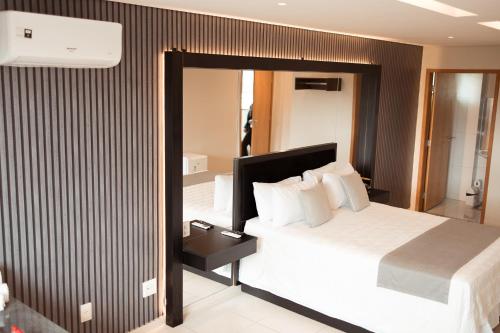 a hotel room with a bed and a mirror at Miami Hotel by H Hotéis - Business in Taguatinga