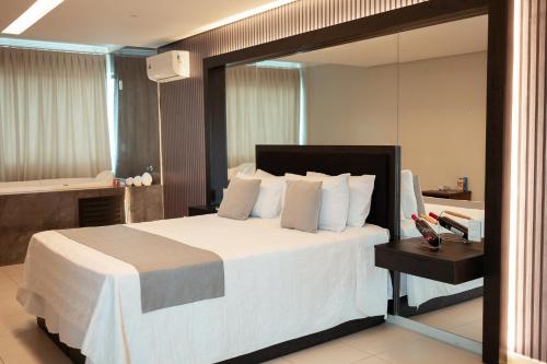 a bedroom with a large white bed and a mirror at Miami Hotel by H Hotéis - Business in Taguatinga