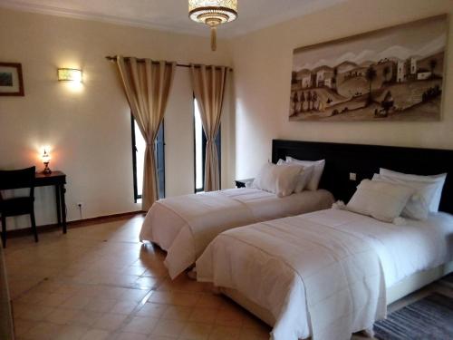- une chambre avec 2 lits, un bureau et des fenêtres dans l'établissement Villa Malaa'ika, à Marrakech