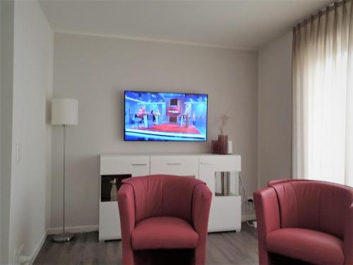 - un salon avec deux chaises et une télévision à écran plat dans l'établissement Haus Nr 11, Ferienhaus Fischerhus, à Wangerland
