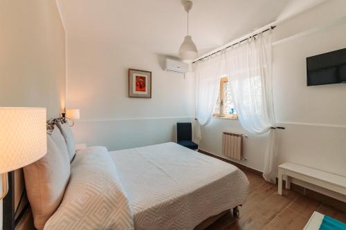 a white bedroom with a bed and a window at Casa Al Vicolo in Taormina