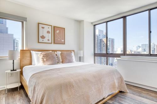 a bedroom with a bed and large windows at Midtown W 2BR w Gym WD nr Times Sq NYC-898 in New York