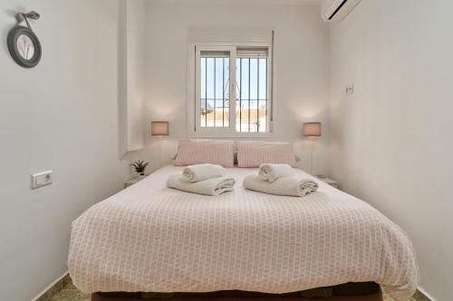 a white bedroom with a bed with two towels on it at Almijarahouse in Nerja