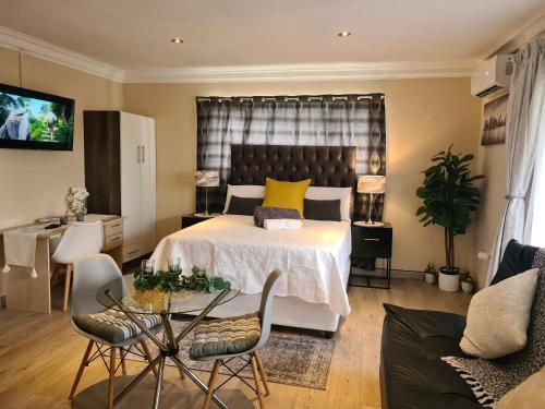 um quarto com uma cama, uma mesa e cadeiras em Halfway Gardens Home em Midrand