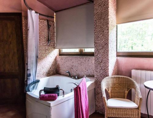 een badkamer met een bad, een stoel en een raam bij HOTEL PASTERAL RIU TER in La Cellera de Ter