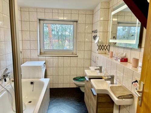 a bathroom with two sinks and a tub and a toilet at Ferienwohnung im Heidepark in Dessau