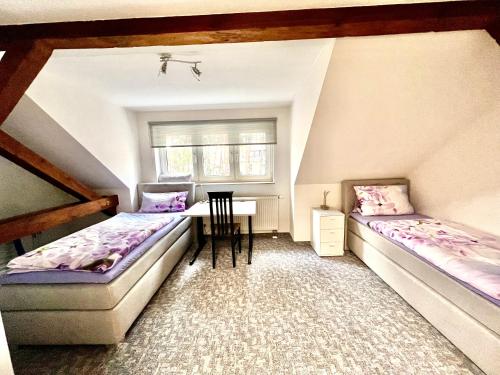 a attic room with two beds and a table at Ferienwohnung im Heidepark in Dessau