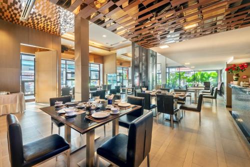 uma sala de jantar com mesas, cadeiras e janelas em M2 de Bangkok Hotel em Bangkok
