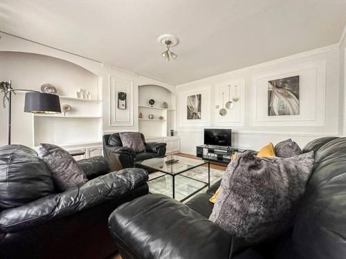 a living room with a leather couch and a table at Newly Refurbished 3 Bed House Near London o2 Arena in London