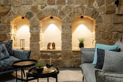 a living room with a stone wall with a couch and a table at Mirsa in ‘Akko