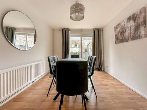 a dining room with a table and chairs and a mirror at Newly Refurbished 3 Bed House Near London o2 Arena in London