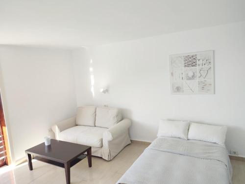 ein weißes Wohnzimmer mit einem Sofa und einem Tisch in der Unterkunft Estudio al Mar in San Marcos