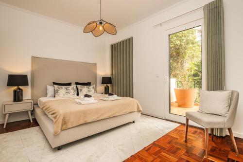 um quarto com uma cama, uma cadeira e uma janela em Recanto da Princesa by Madeira Sun Travel no Funchal