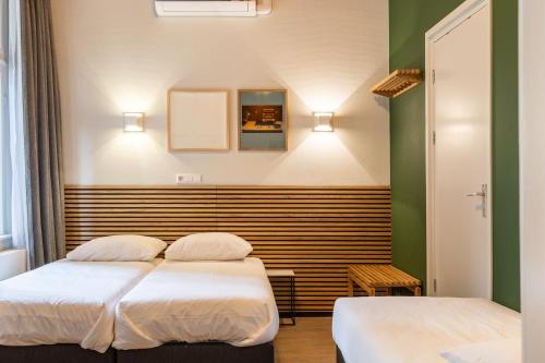 twee bedden in een kamer met groen en wit bij Weber Hotel in Amsterdam
