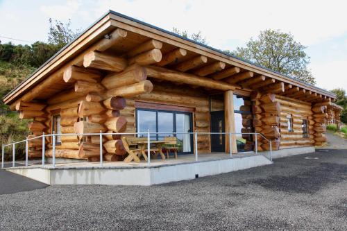 a log cabin with a large pile of logs at Aurora in Bushmills