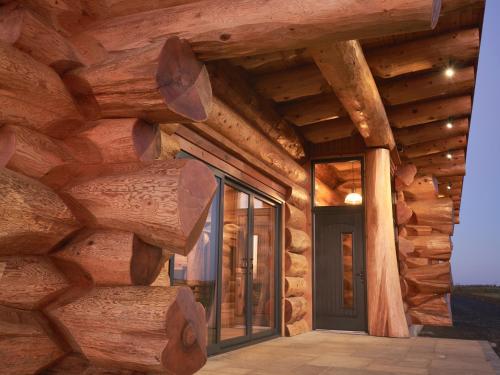 a log house with glass doors and windows at Aurora North Coast in Bushmills