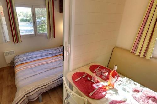 a small room with a bed and a table with glasses at Camping Domaine de la Paille Basse - Maeva in Souillac