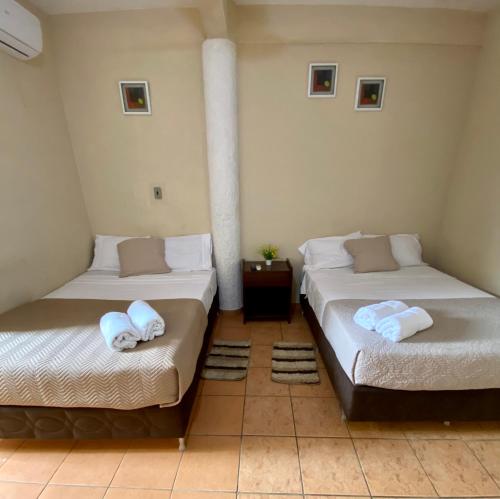 a room with two beds with towels on them at Casa Glamour in Trinidad