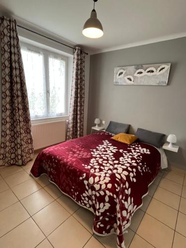 a bedroom with a bed with a red comforter and a window at Domaine de la moriniere in Commequiers