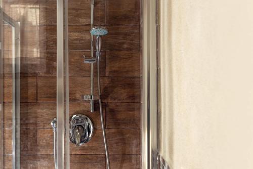 a shower in a bathroom with a wooden wall at Mugello Vacanze Appartamenti Indipendenti in Scarperia
