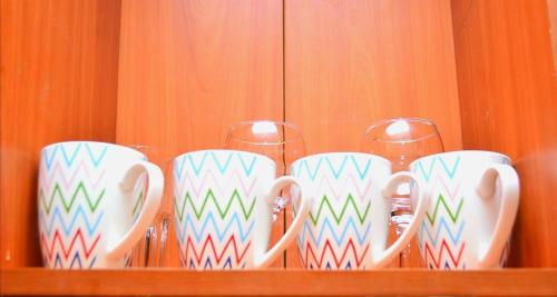 a row of cups and wine glasses on a shelf at Elegant 1br Milimani - Fast Wifi in Kisumu