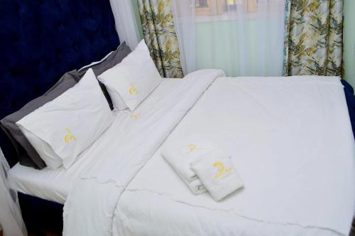 1 dormitorio con 2 camas blancas con sábanas y almohadas blancas en Elegant 1br Milimani - Fast Wifi en Kisumu