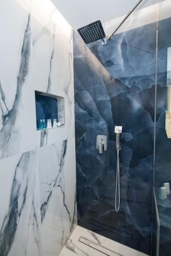 a bathroom with a shower with marble tiles at RAFAELA SUITES in Flogita