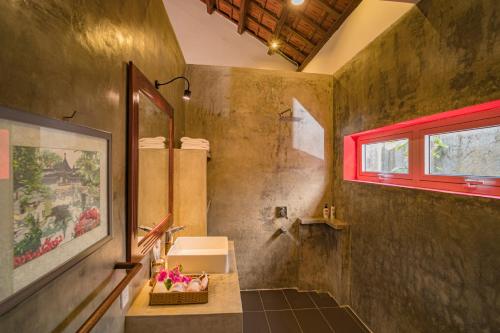 ein Bad mit einem Waschbecken und einem roten Fenster in der Unterkunft Be's Beach House An Bang in Hoi An