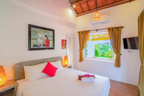 ein Schlafzimmer mit einem weißen Bett mit roten Kissen und einem Fenster in der Unterkunft Be's Beach House An Bang in Hoi An