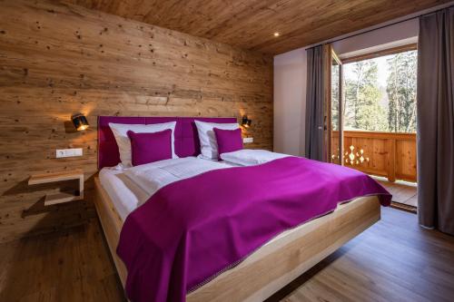 ビショフスヴィーゼンにあるBergbauernhof Schoberlehenのベッドルーム1室(紫のシーツが敷かれた大型ベッド1台付)