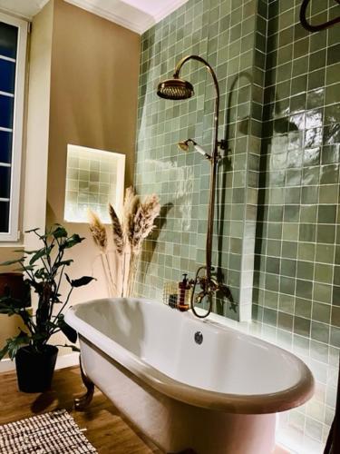 La salle de bains est pourvue d'une baignoire et de carrelage vert. dans l'établissement Domaine de la Croix de Saint Lambert, à Poix-Terron