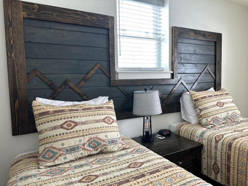 1 dormitorio con 2 camas, cabecero y lámpara en Pine Lodge en Encampment