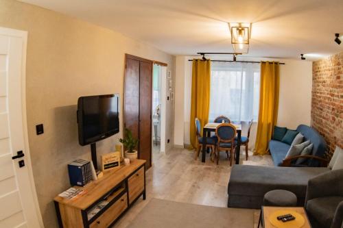 een woonkamer met een bank en een tv bij Loft Apartament ULA in Elblag
