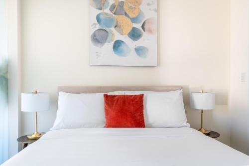 a bedroom with a white bed with a red pillow at Kasa Alexandria Washington in Alexandria