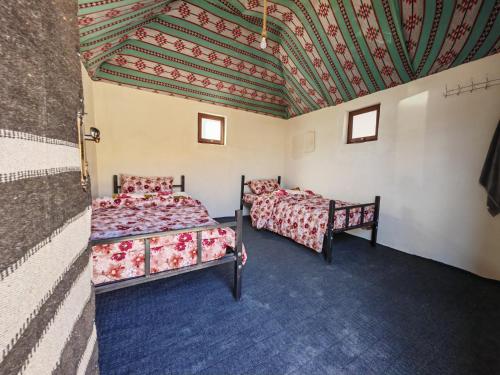 two beds in a room with a ceiling at Namla Bedouin Camp in Umm Şawwānah