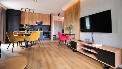 a living room with a table and chairs and a television at Residence Polanica z sauną, Sun & Snow in Polanica-Zdrój