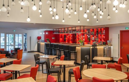 a restaurant with wooden tables and chairs and red cabinets at LE M HOTEL & SPA HONFLEUR in Honfleur