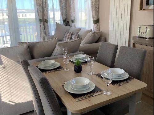 a wooden table with plates and wine glasses on it at Sea La Vie in Cayton