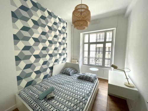a small bedroom with a bed and a checkered wall at T5 COEUR DE VILLE in Besançon
