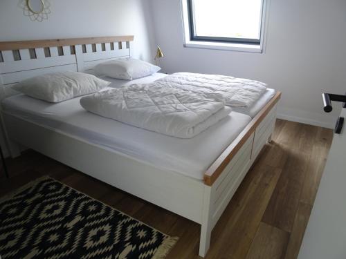 a white bed with white sheets and pillows on it at Kustverhuur, Park Schoneveld, Zeester 49 in Breskens
