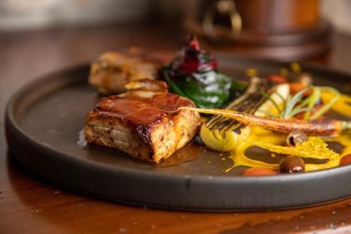 a plate of food with meat and vegetables on a table at Locanda di Corte in Bosa