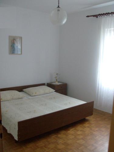 a bedroom with a bed and a window at Apartments Ajka in Tisno