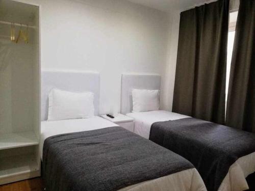 Una habitación de hotel con dos camas y una ventana. en Apartamentos Internacional, en Coímbra