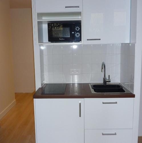 une cuisine blanche avec un évier et un micro-ondes dans l'établissement Tour Eiffel Beaugrenelle, à Paris