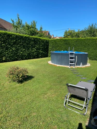 une chaise assise dans l'herbe à côté d'une piscine dans l'établissement Chez Nanou, à Marmagne
