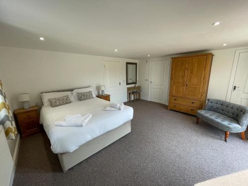 um quarto com uma grande cama branca e uma cadeira em High Lodge em Watchet