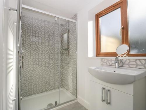 uma casa de banho com uma cabina de duche em vidro e um lavatório. em High Lodge em Watchet