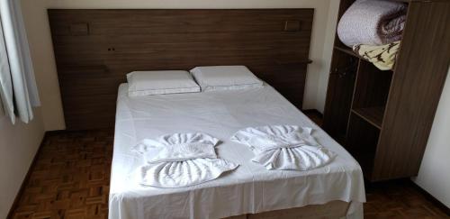 ein Bett mit weißer Bettwäsche und Kissen darauf in der Unterkunft Hotel Flórida in União da Vitória