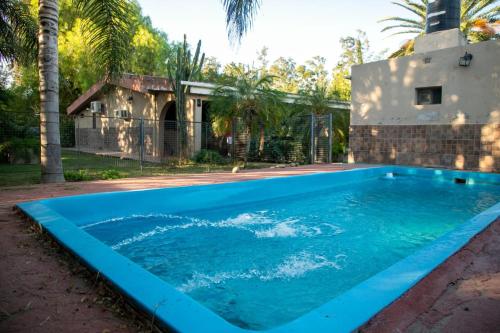 uma piscina com água azul em frente a uma casa em FINCA EL BRACO em Santiago del Estero